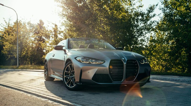 Where to Buy Genuine BMW Parts in the UK Cheaper? Silver BMW M4 convertible parked beside a tree-lined road in low evening sunlight
